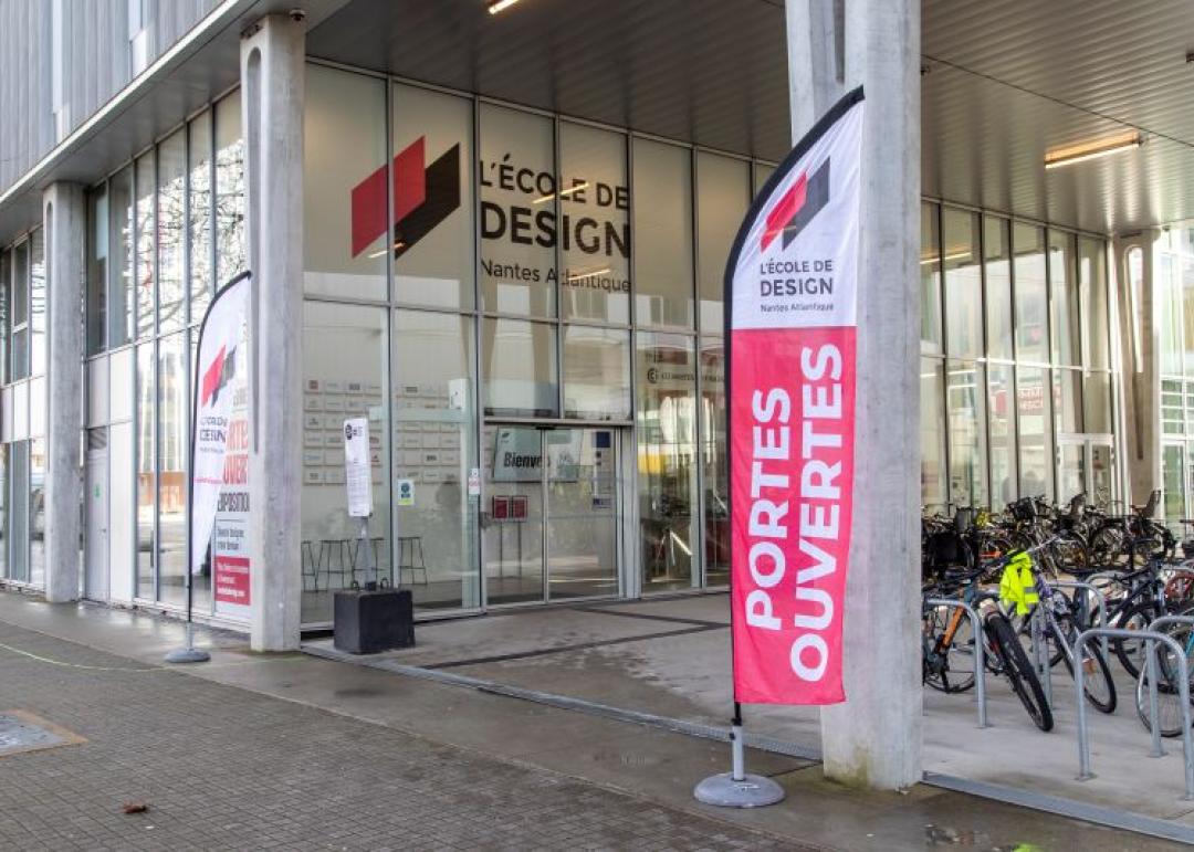 Photo de l'extérieur de l'école où l'on voit l'on l'entrée de l'école avec une flamme où s'est écrit : portes ouvertes
